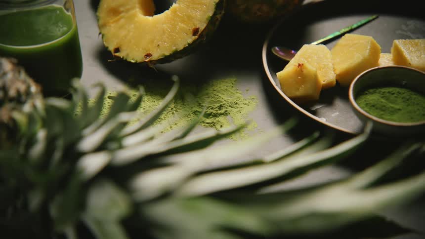 A whole pineapple sits near the plate of pineapple chunks