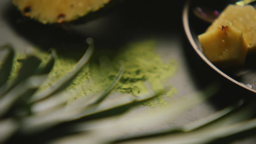 Pineapple slices and green matcha tea powder over a table coming into focus