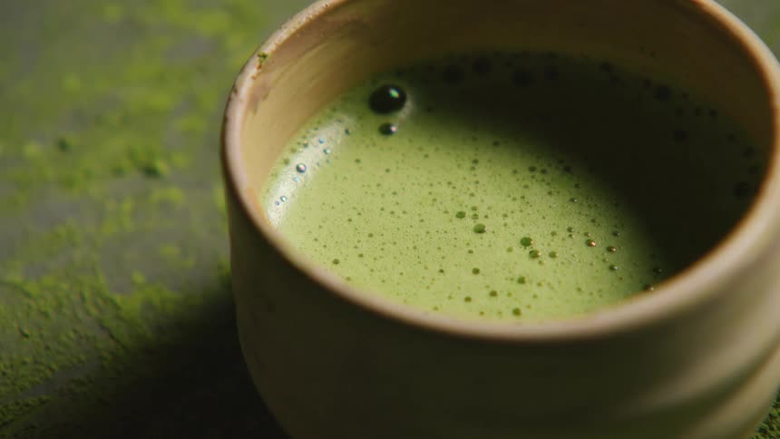 Hand picking up a mug with green tea
