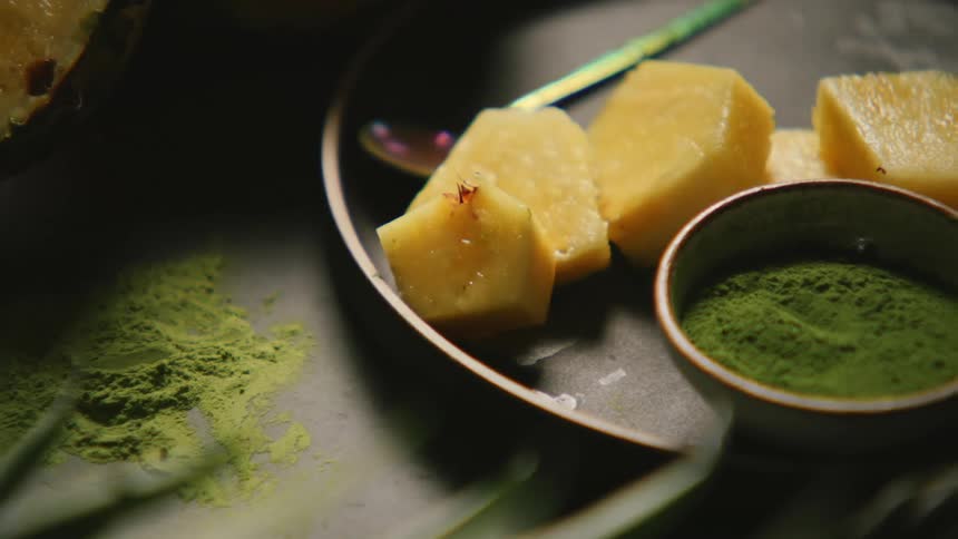 Juicy chunks of pineapple sit next to a small bowl of vibrant green powder