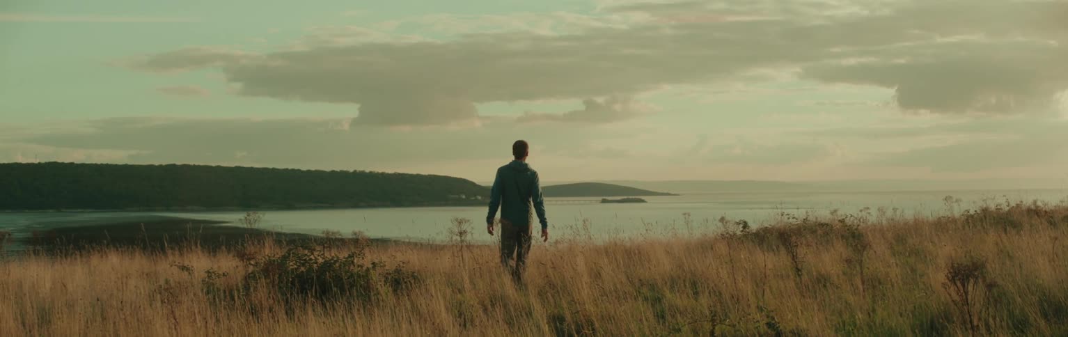 Man walking through a natural area with a view of the sea