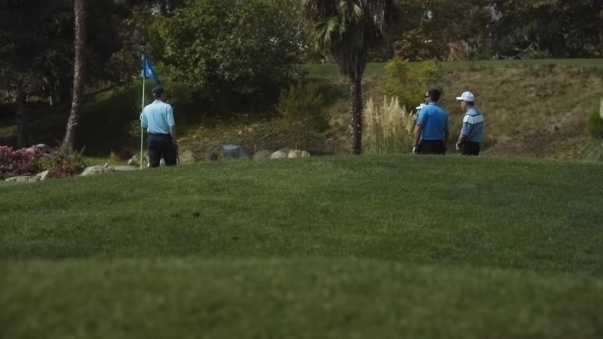 Golfers stand near a hole
