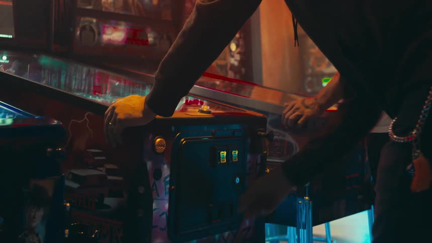A close up of a person playing a pinball machine in an arcade