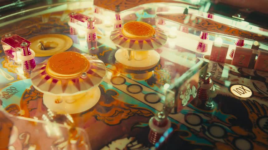 Vibrant lights reflect off the shiny surface of a vintage pinball machine