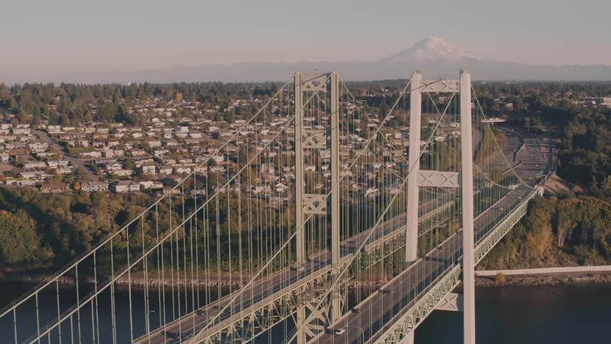 Tacoma narrows bridge rises majestically over the calm waters connecting urban and natural landscapes in the golden light of dusk