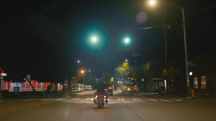 Person riding a motorcycle on a city street at night
