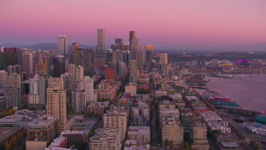 A panoramic view of seattle at sunset featuring the downtown area under a sky with pink hues