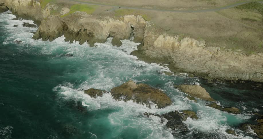 Aerial view of turbulent and strong weapons hitting the rocky coast