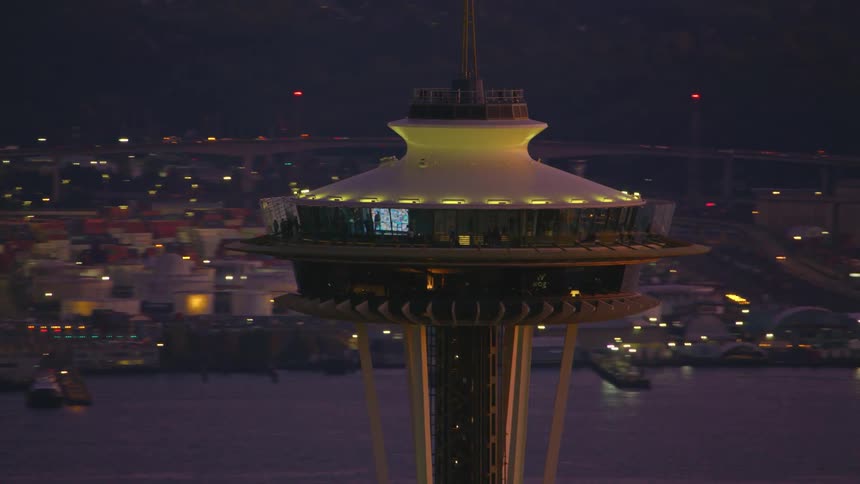 A closeup view of the space needle in seattle washington illuminated at dusk with the cityscape in the background
