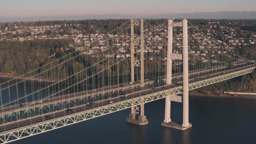 Aerial view of two large bridges above a sea channel and an urban city in the background
