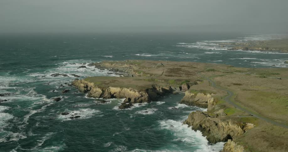 Area of land surrounded by sea with strong waves on a cloudy day