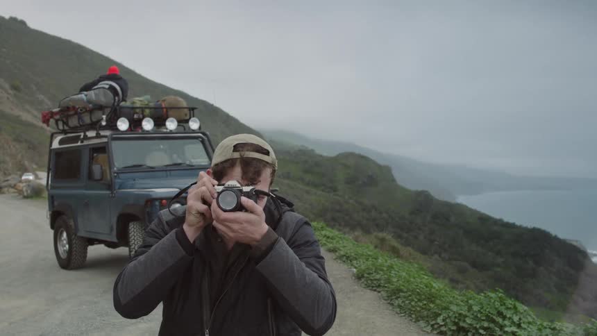Man in front of a car takes a photograph