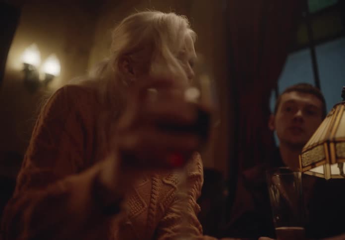 Woman next to a man in a restaurant drinking a glass of red wine