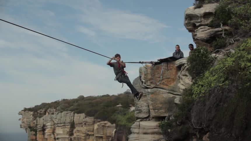 A man uses a zip line while others watch