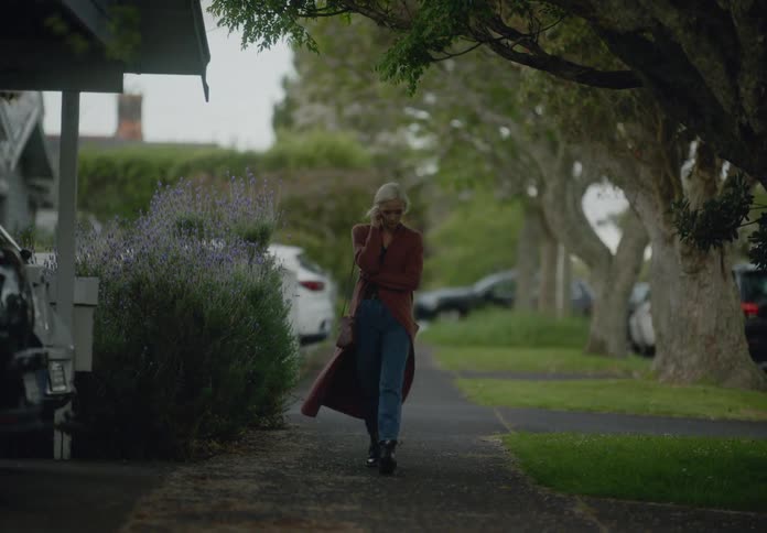 Woman walking dejectedly on the sidewalk of a residential neighborhood