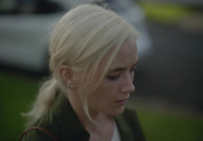 Portrait of a blonde woman walking on the sidewalk with a sad facial expression