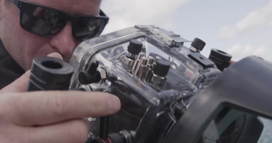A person holding an underwater camera and checking it out
