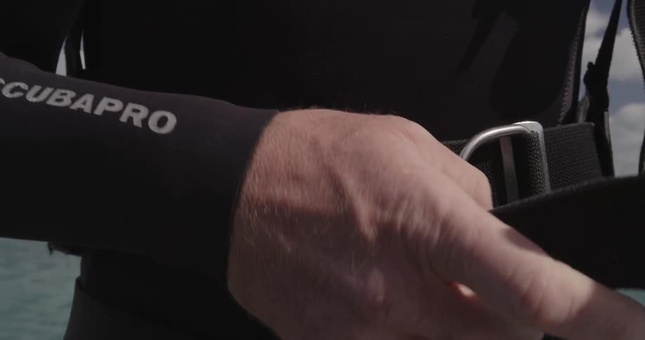 A diver tightens the belt on his wetsuit