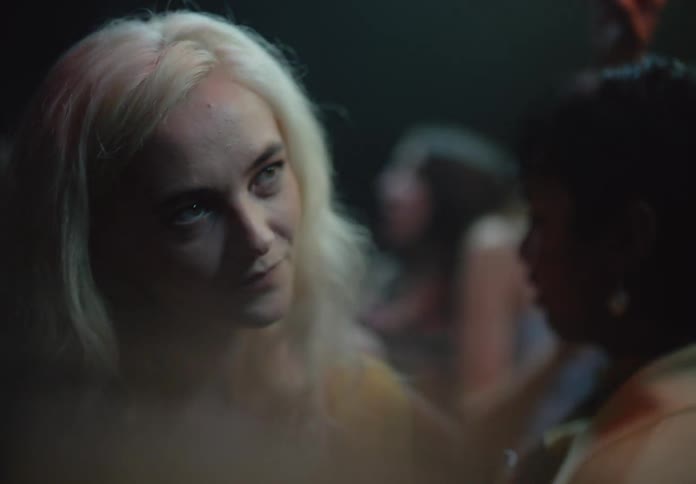 A blonde woman dances with someone in a packed nightclub