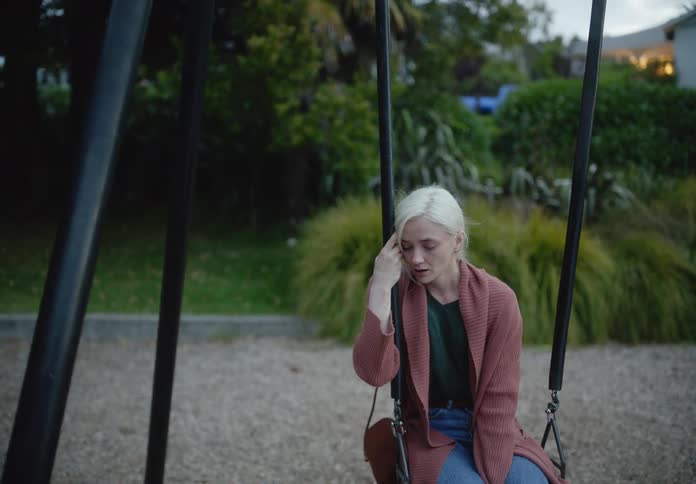 Woman crying dejectedly while sitting on a swing at a playground