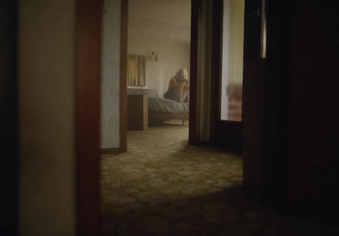 Woman sitting on a bed in a bedroom with her head down
