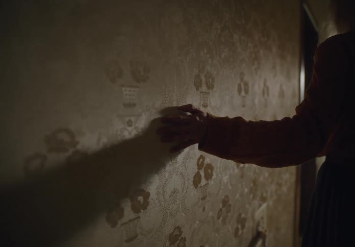 Woman leaning her hand against the wall of a room in the house in a melancholic manner
