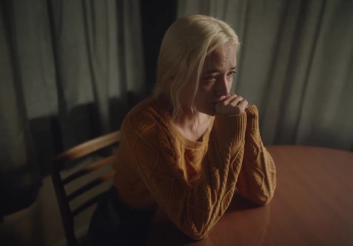 Blonde woman sitting at a table with a crying expression