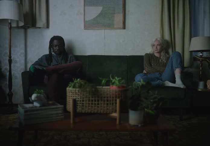 Man and woman sitting on the end of a sofa in the living room without eye contact