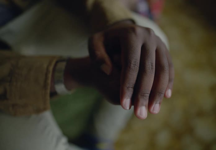 A mans hand adorned with a watch and shirt cuff delicately holds a small ornate silver heartshaped necklace in his palm