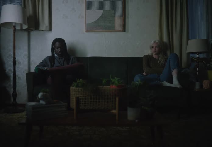 Woman and a man sitting on either end of a sofa looking melancholic
