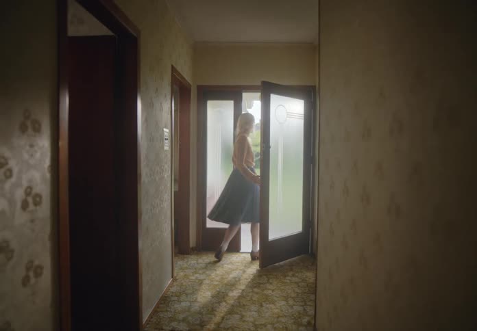 Woman looks back before exiting through the glass doors of a house