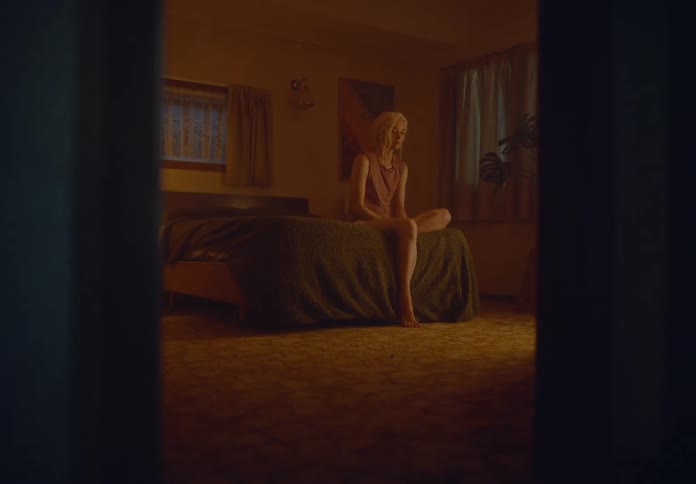 A footage of a lady sitting on the bed in the room