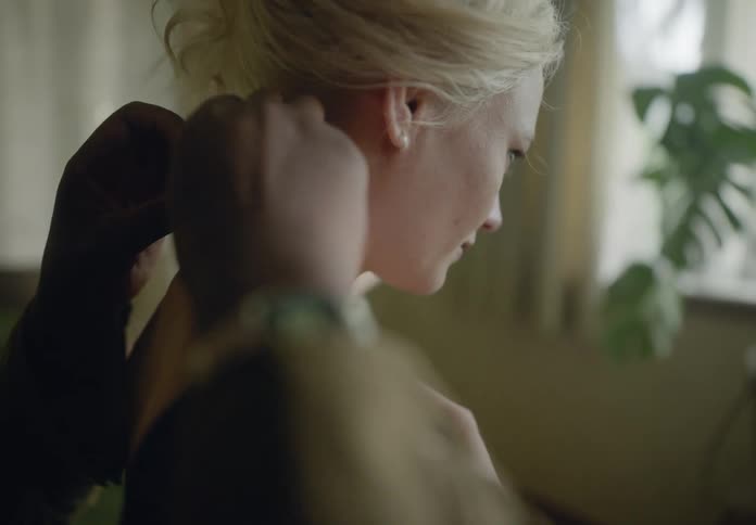 Blonde woman holding her hair up as her boyfriend puts a necklace around her neck