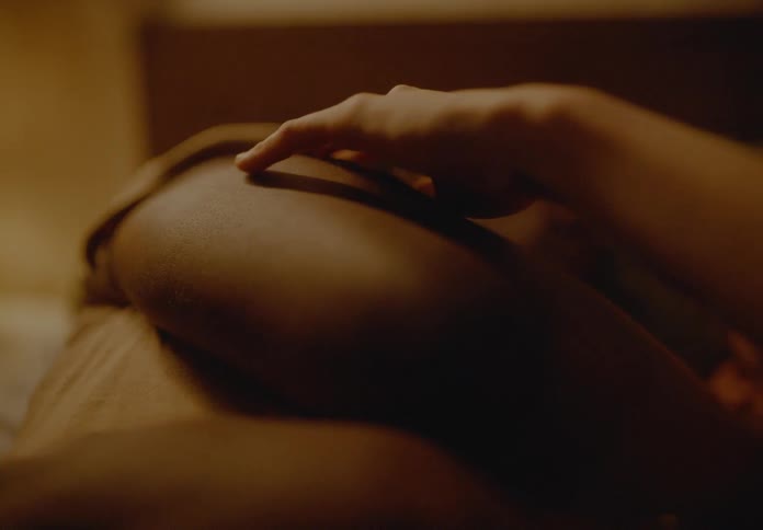 Woman and man lie on the bed while she caresses his arm