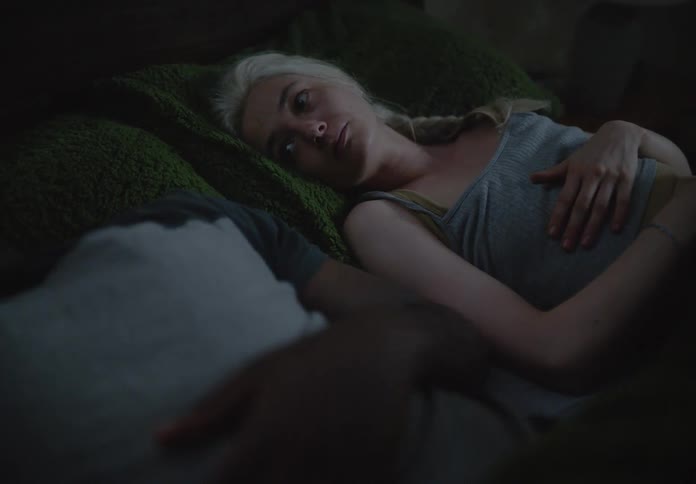 A couple in bed with the woman trying to hug the man who turns away