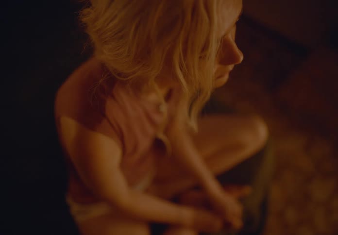 Top view of a blonde woman sitting in a dimly lit room of the house