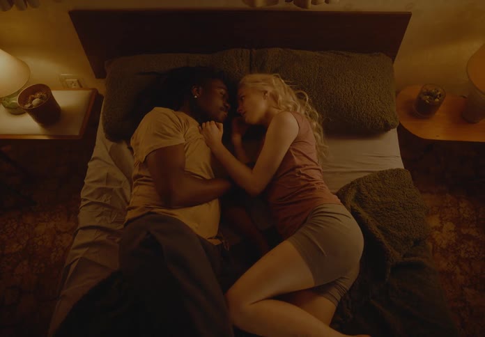 A couple lay together on the bed touching each other on the face romantically