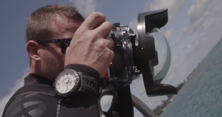 A scuba diver is checking out his camera during the day
