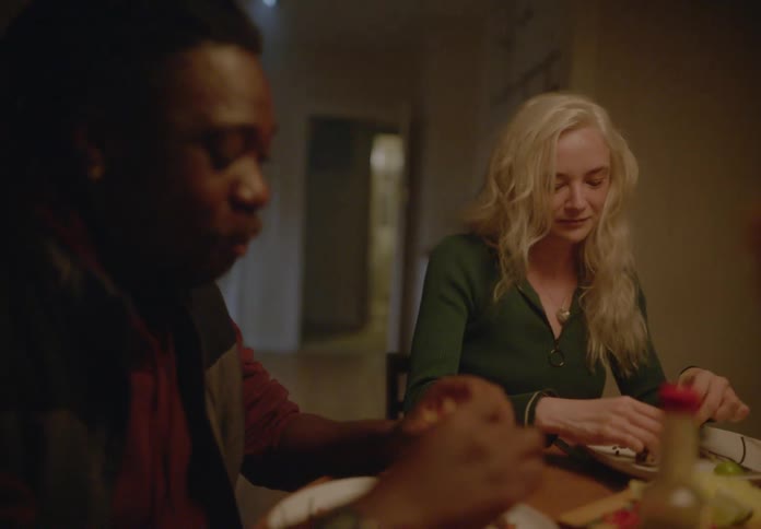 A couple sits at a table at home enjoying a meal and having a conversation