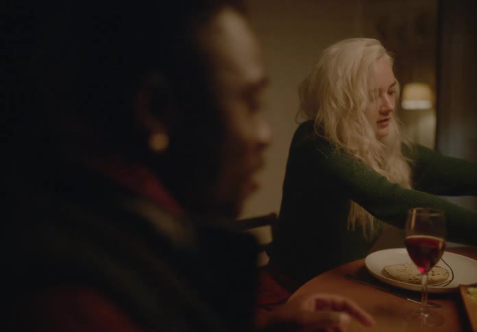 Man and a woman sitting at a table served with food and glasses of red wine