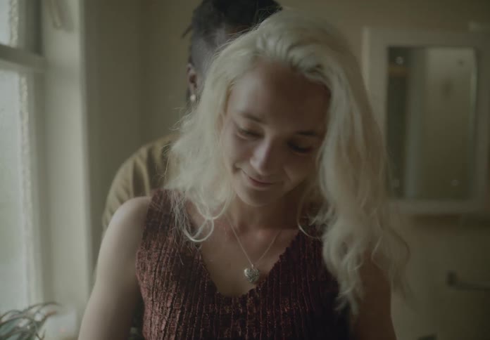 Smiling couple hugs and cuddles while standing near a window at home