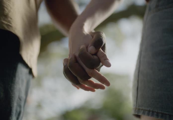 Man and woman gently holding hands with their torsos visible