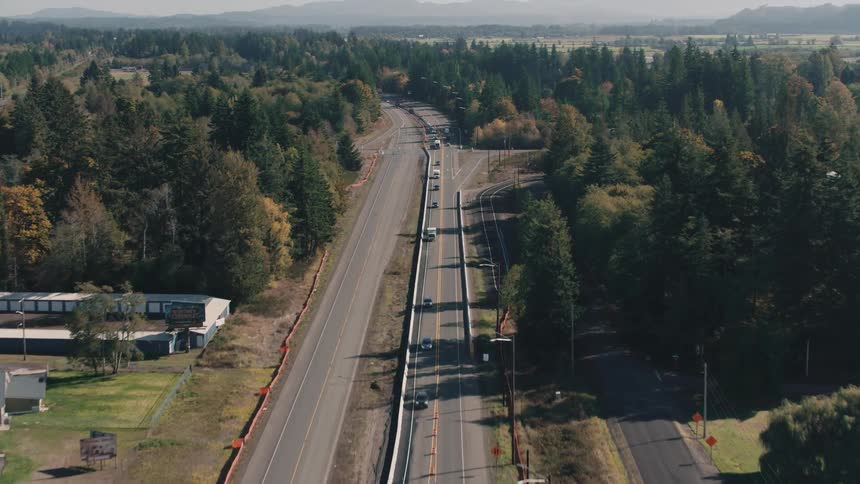 Aerial view of a highway with vehicle traffic in an area surrounded by tall trees