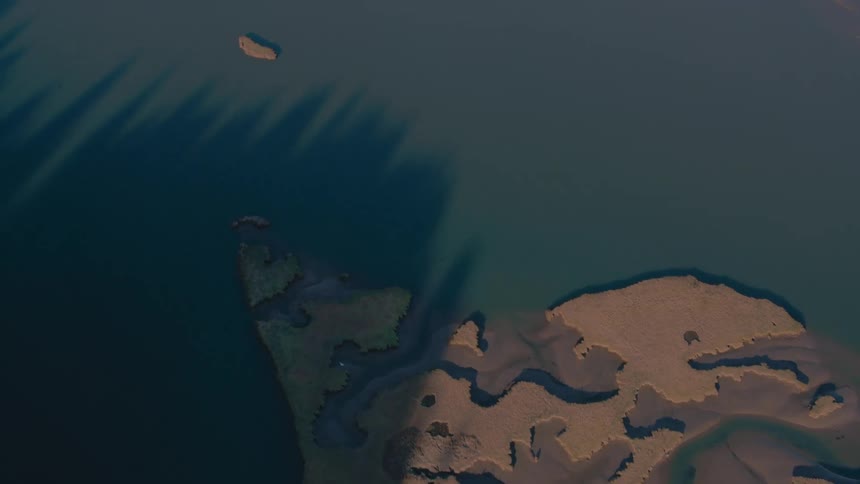 Raised causeway winds past coastal terrainacross from a peninsula during the daytime