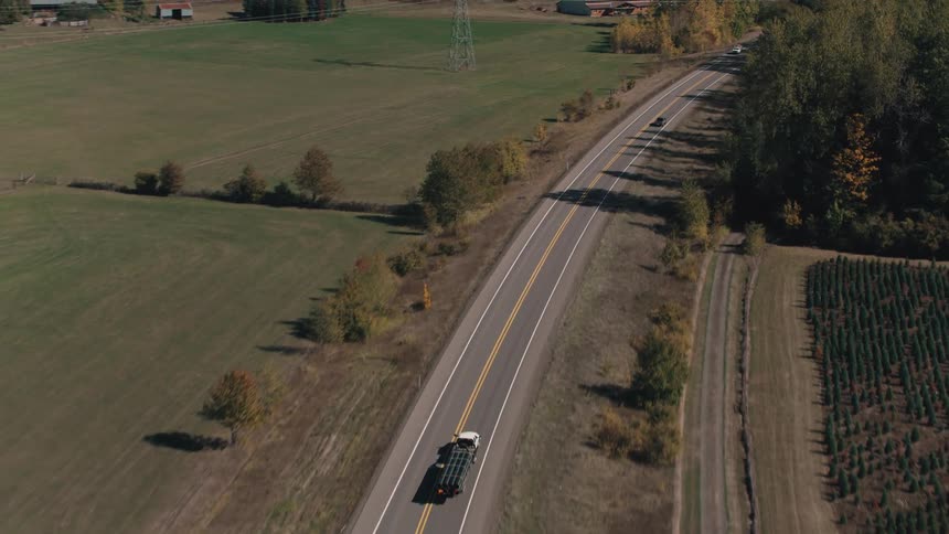 Vehicle traffic on a highway that passes between hills and dense forests