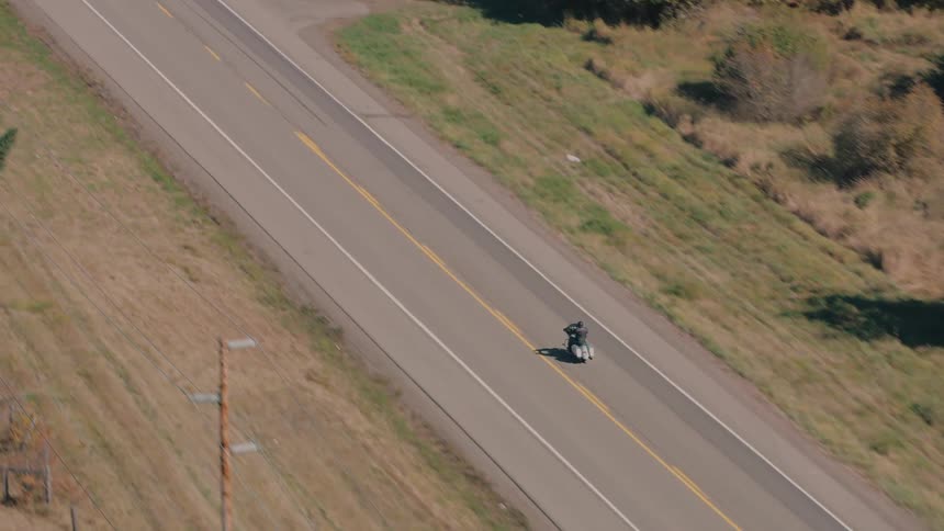Aerial view of a person on a motorcycle traveling along a highway