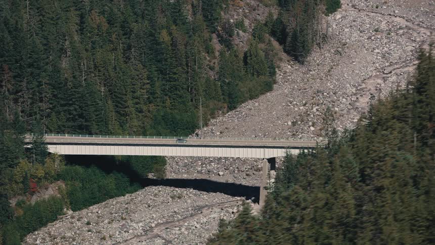 Bridge over gravel connecting dense forests and vehicle traffic