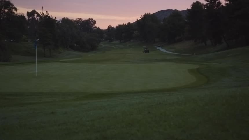 A golf cart drives on a golf course