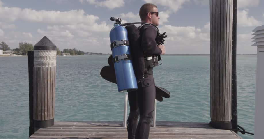 A scuba diver walks to the end of the pier