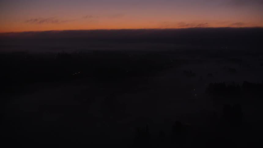 Bright canvas paneled glider flies over a fog covered forest under a red tinted sky